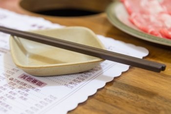 Chopsticks and serving dish on menu in Chinese restaurant