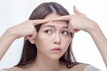 Chinese woman squeezing a spot on her forehead