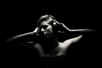 gorgeous woman in black and white listening to music. gorgeous woman in black and white tense light listening to music