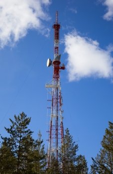 TV Transmission tower in  forest  against the background of blue sky