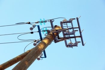 A pillar of power line with a line isolator against the sky