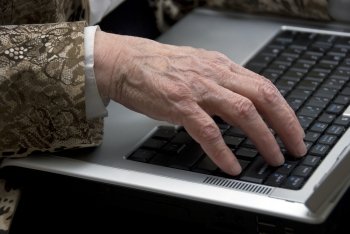 hand of a woman older then 80 , working on a mobile laptop