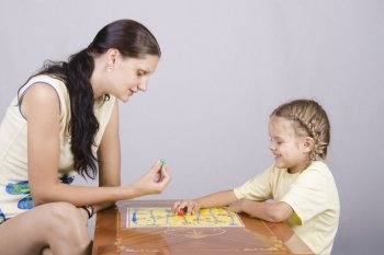 Mother and daughter sitting at a table and play a Board game