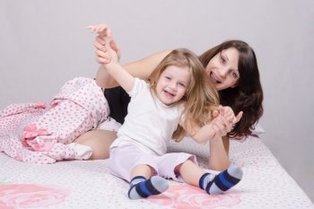 Mom and daughter with an excellent mood sitting on the bed