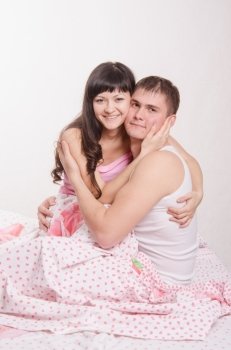 Young couple sitting in bed and hugging each other