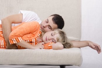Young couple sleeping on the couch. The guy took her in his arms from behind.
