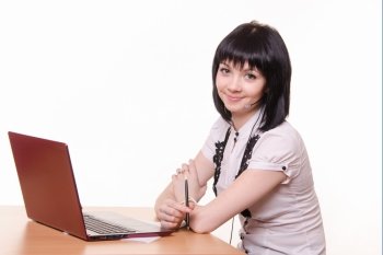 Cute little girl sitting at a table in the call center with laptop in white blouse. Smiling girl - call-center employee at the desk