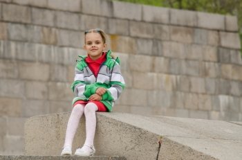 A girl of six years walking on the embankment. Girl sitting a granite embankment on ramp