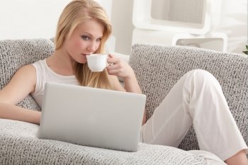Young Beautiful Blond Woman Drinking Her Coffee and Surfing the Net at Home