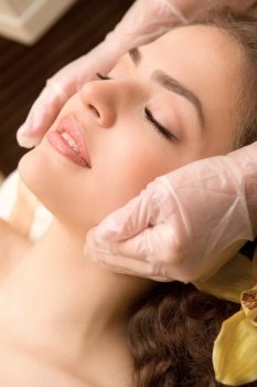 Young relaxing beautiful woman having facial lymphatic massage