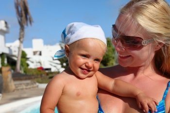 portrait of smilling mother and daughter near pool. Focus on the baby
