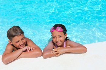 Happy children,  girl and boy, relaxing on the side of a swimming pool wearing pink and grey goggles