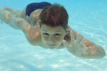 Boy swimming underwater in swimming pool 