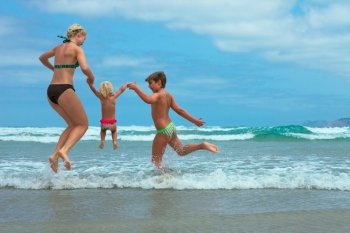 Mother and two kids  jumping on beach 