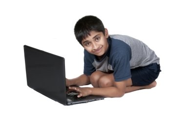 An handsome Indian kid having fun with laptop