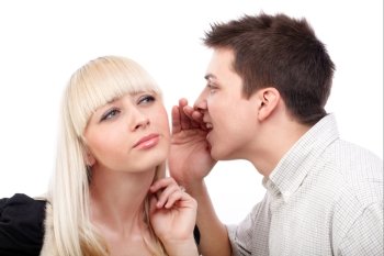 Portrait of a  young man whispering a secret to a cute woman against white 
