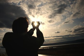 man holding a sun in his hands against the sky