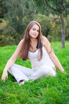 beautiful young woman sitting on green grass