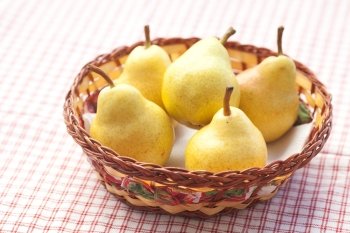 pears in a wooden basket  lying on a plaid fabric 