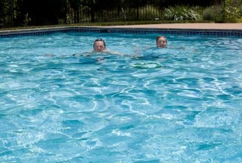 Baby boomer couple floating in a backyard swimming pool on a hot summers day