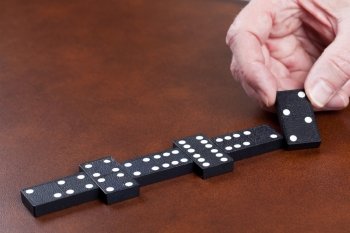 Macro image of dominos on a leather table in the middle of a game with hand placing a tile