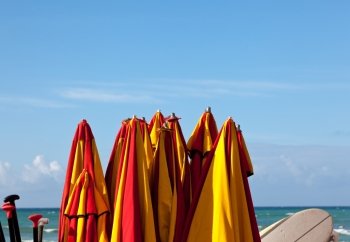 Set of beach umbrellas in a stack by blue ocean