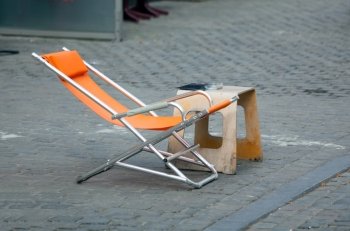 Orange relaxing deckchair on cobbled road in Belgium
