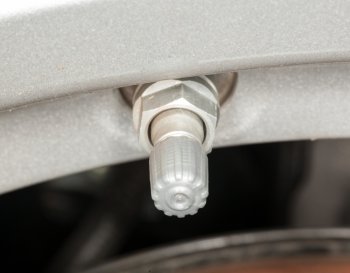 Silver colored tyre pressure valve on alloy wheel of car