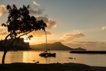 Early morning sunrise at dawn illuminates clouds over Diamond Head and Waikiki Beach area of Oahu in Hawaii