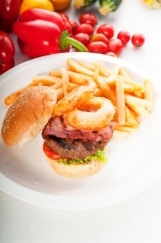 classic american hamburger sandwich with onion rings and french fries,with fresh vegetables on background, MORE DELICIOUS FOOD ON PORTFOLIO
