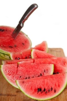 fresh ripe watermelon sliced on a  wood table with knife over white background