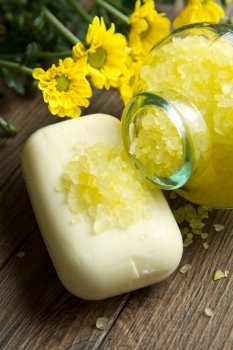 Soap and yellow flowers on wooden table