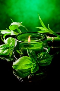 photo of candle with basil flavour on black glass table 