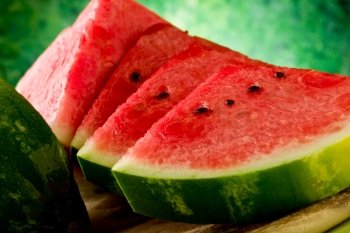 photo of fresh delicious watermelon on chopping board with green background