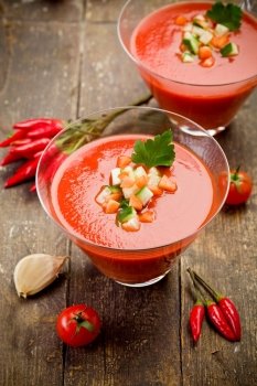 Delicious gazpacho on wooden table with fresh vegetables