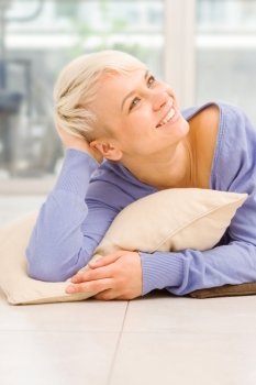 Photo of a smiling woman with short hairs laying on a pilow