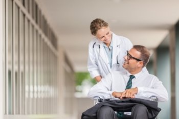 Photo of female doctor pushing businessman on wheelchair