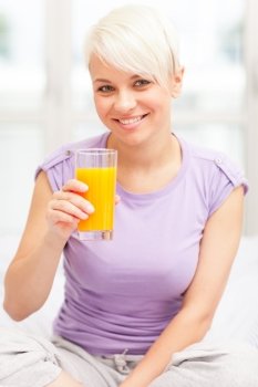 Photo of blonde woman having juice for breakfast