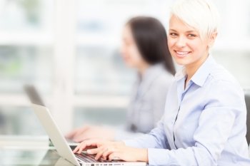 photo of female blonde employee working on her computer in office 