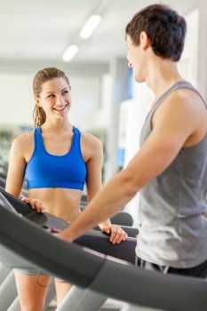 Female fitness instructor smiling towards young man on a treadmill