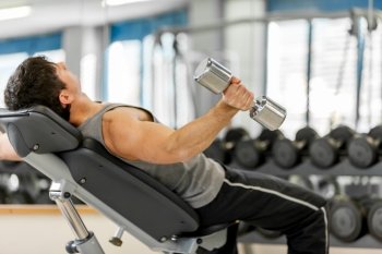 Photo of young caucasian man working out his arms with dumbbells