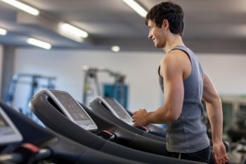 Photo of caucasian trained man running on a treadmill in the fitness studio