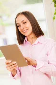 Photo of caucasian smiling woman with a pink shirt looking at her tablet pc