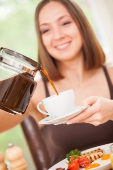 Closeup of smiling brunette woman pouring a cup of coffee