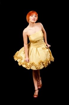Beautiful Caucasian redhead woman in yellow cocktail dress in playful pose, isolated