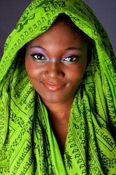 The face of an innocent smiling beautiful young African-American woman with green headwrap and purple-green makeup, isolated