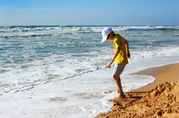 Boy playing with sand on the seashore