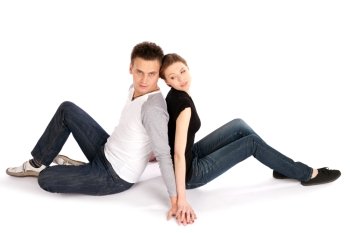 Young attractive loving couple sitting back to back on white isolated background