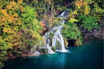 Scenic waterfall in a beautiful picturesque scenery of the autumn forest
