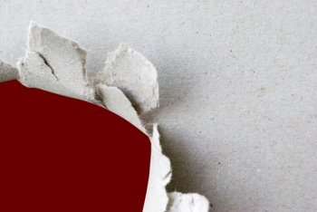torn hole in white sheet of paper with red background and copyspace